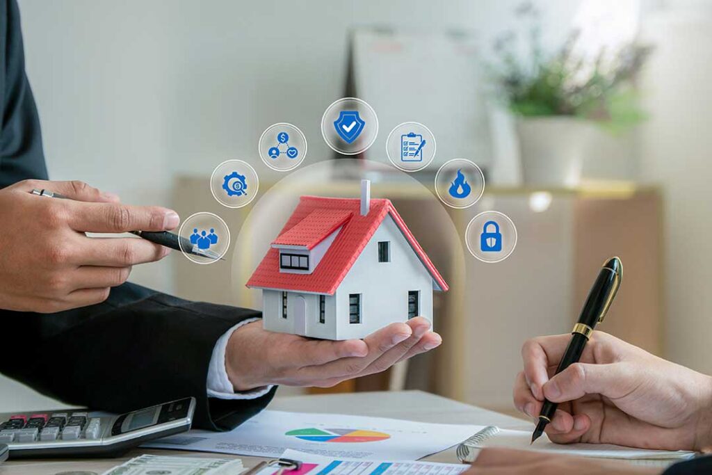 A person reviewing car insurance documents and an auto loan statement at a kitchen table.