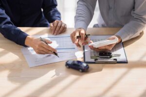 A person reviews insurance documents, receipts, and a home inventory checklist at a kitchen table.