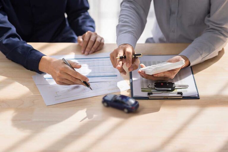 A person reviews insurance documents, receipts, and a home inventory checklist at a kitchen table.